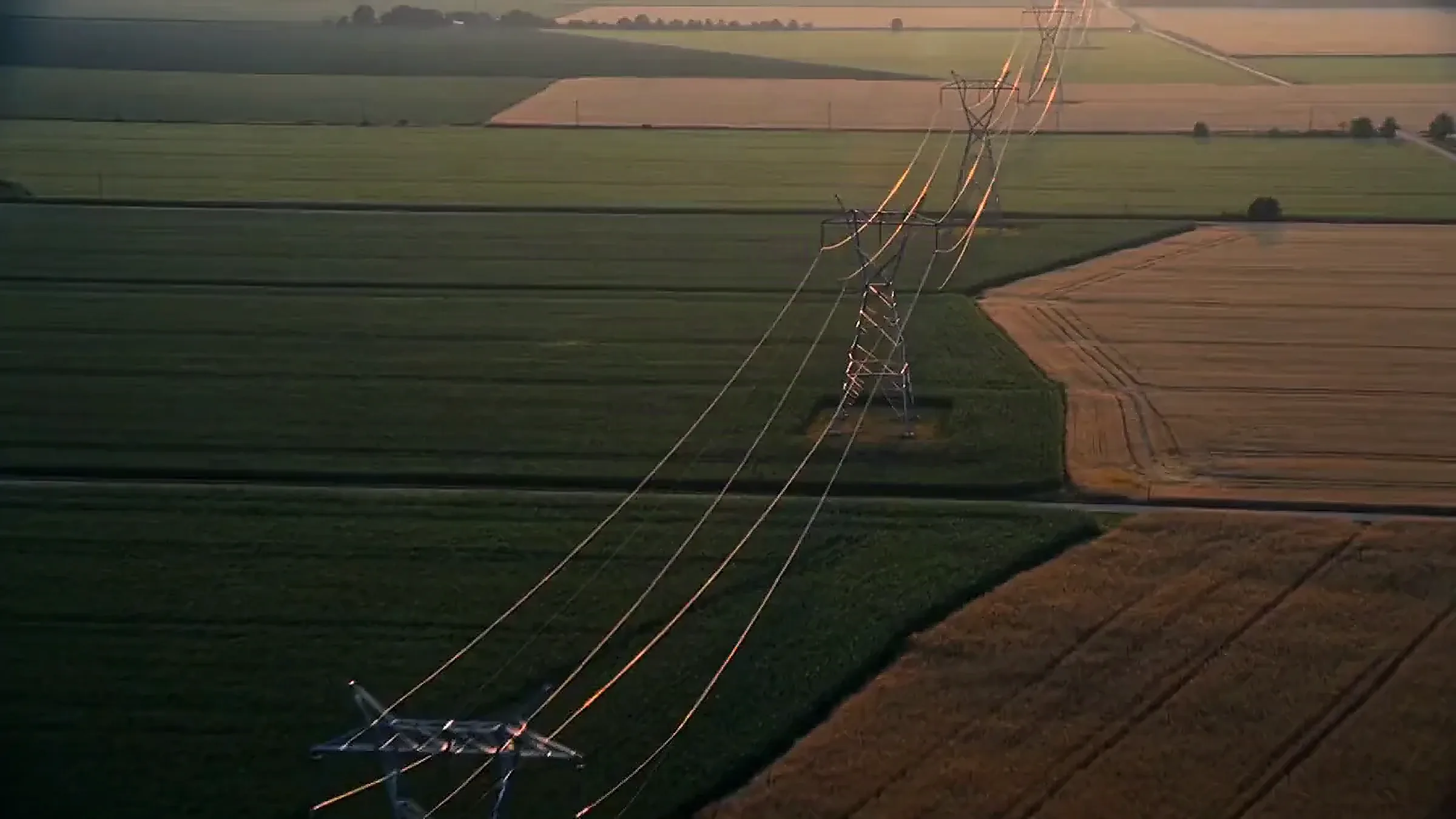 Aerial view along a transmission line over farmland at first light