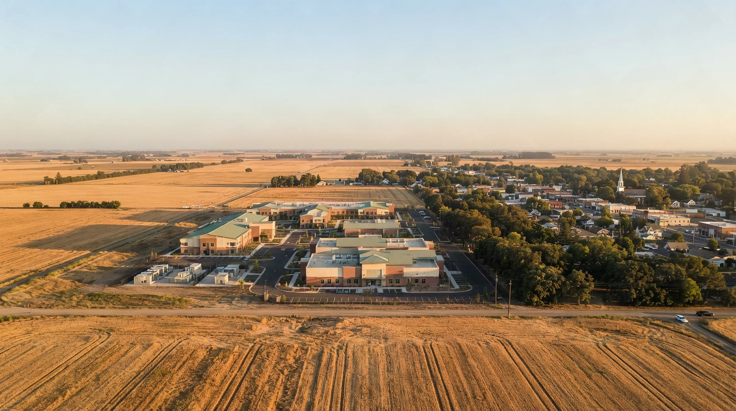 Aerial view at golden hour of a data center campus on the edge of a small farming town